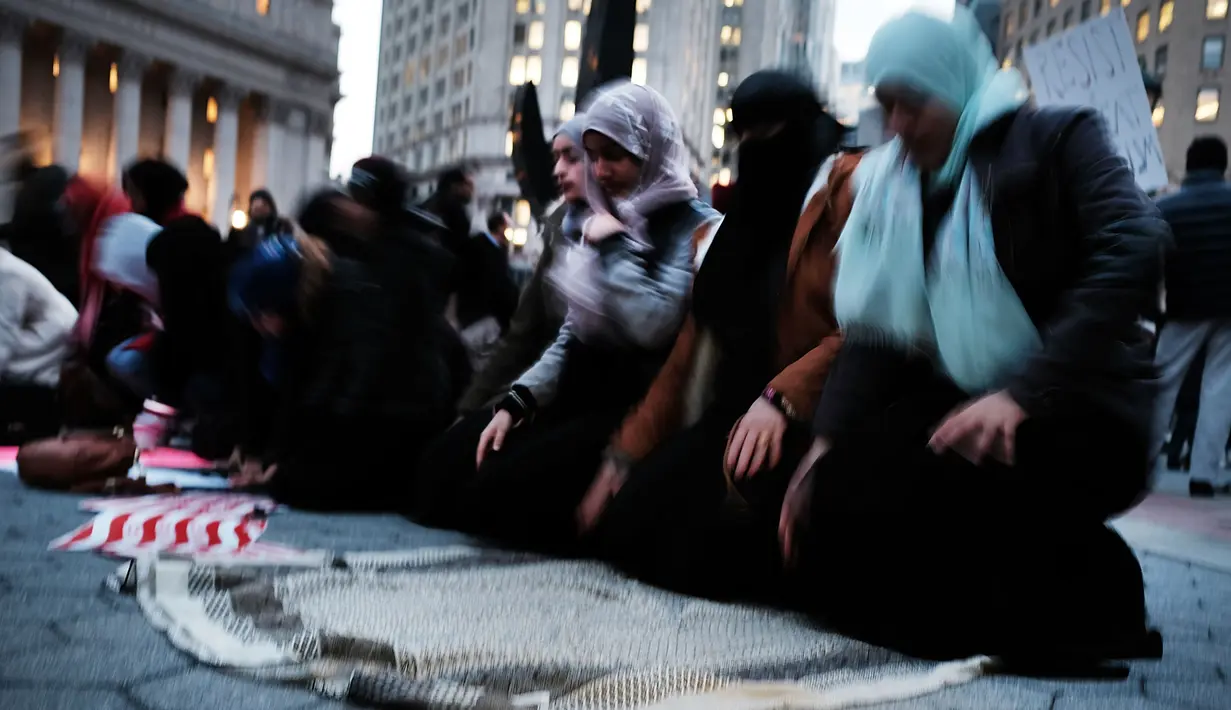 Wanita muslim menggelar salat berjemaah sebelum melakukan aksi protes di Manhattan, New York (1/2). Mereka juga mengecam kebijakan Donald Trump terkait larangan imigran dari negara mayoritas muslim masuk ke AS. (AFP/Spencer Platt)