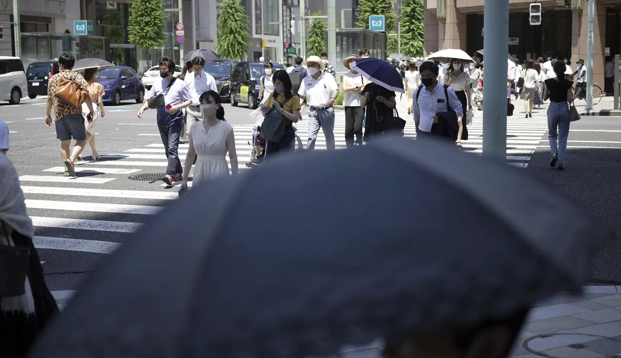 Orang-orang berjalan di atas penyeberangan pejalan kaki di bawah terik matahari di Tokyo, Selasa (28/6/2022). Pemerintah Jepang mengeluarkan peringatan untuk kemungkinan pemadaman listrik di wilayah Tokyo pada hari Senin (27/6), meminta kantor dan penduduk untuk menghemat energi karena wilayah ibu kota dilanda panas terik. (AP Photo/Eugene Hoshiko)