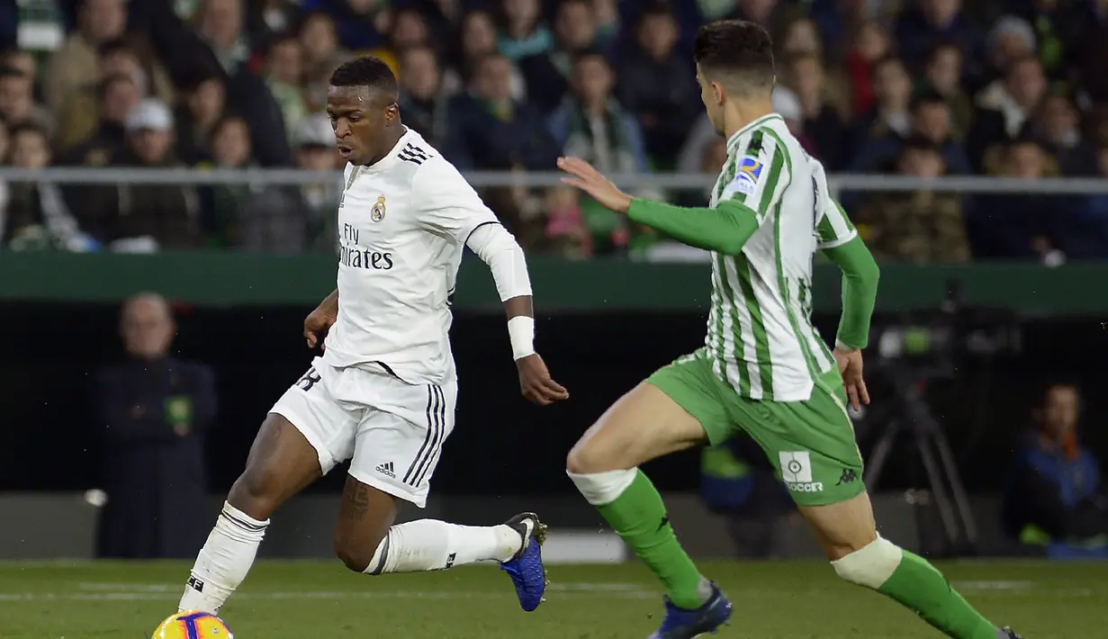Vinicius jr mencoba melewati hadangan pemain Real Betis pada laga lanjutan La Liga Spanyol yang berlangsung di stadion Benito Villamarin, Senin (14/1). Real Madrid menang 2-1 atas Real Betis. (AFP/Cristina Quicler)