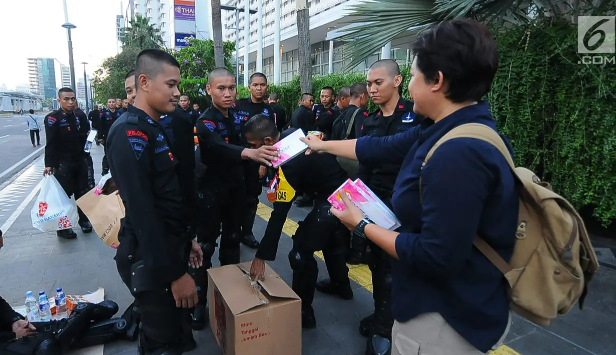 Relawan TKN Jokowi-Ma'ruf Amin membagikan multivitamin kepada aparat kepolisian yang melakukan penjagaan di Bundaran HI, Jakarta, Jumat (24/5/2019). Mereka juga membagikan makanan berbuka puasa sebagai bentuk kepedulian untuk aparat yang telah menjaga keamanan di Jakarta. (Liputan6.com/Angga Yuniar)