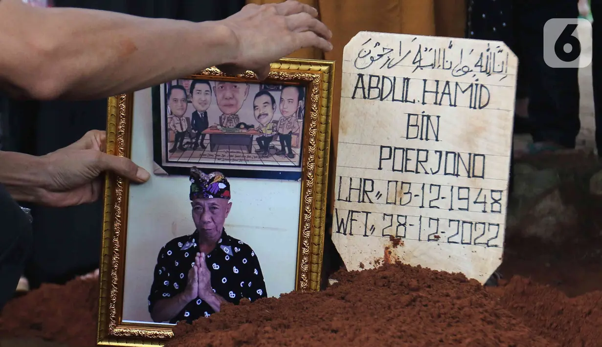 Foto almarhum Abdul Hamid alias Pak Ogah diletakan di atas makamnya di TPU (Tempat Pemakaman Umum) Jatisari, Bekasi, Jawa Barat, Kamis (29/12/2022). Pak Ogah salah satu pengisi suara dalam serial film Si Unyil meninggal pada (28/12/2022) di usia 74 tahun. (Liputan6.com/Herman Zakharia)
