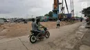 Pengendara motor melintas di area tanggul pantai di Kamal Muara, Jakarta, Rabu (26/12). Pembangunan tanggul pantai di Kamal Muara dengan panjang 740 meter yang akan rampung pada 2020. (Liputan6.com/Herman Zakharia)