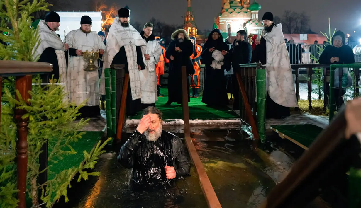 Seorang pendeta Kristen Ortodoks membuat tanda salib saat mandi dalam air es pada perayaan Epiphany di Gereja Tritunggal Mahakudus, Ostankino, Moskow, Rusia, 18 Januari 2023. Penganut Kristen Ortodoks di Rusia merayakan Hari Raya Epiphany dengan membenamkan diri ke dalam air dingin untuk memperingati pembaptisan Yesus Kristus di Sungai Yordan. (AP Photo/Alexander Zemlianichenko)