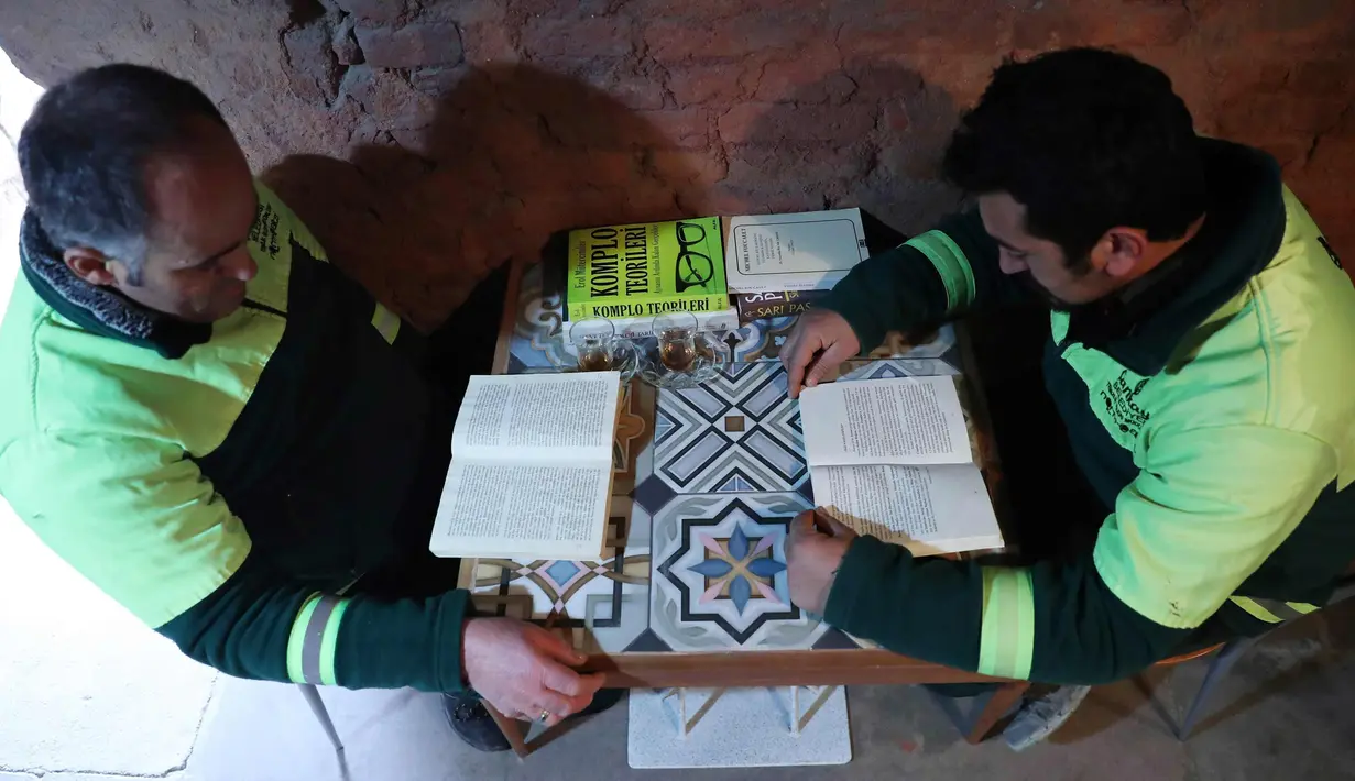 Petugas kebersihan membaca buku di perpustakan tempat mereka bekerja di distrik Cankaya, Ankara, Turki (9/1).Beberapa petugas ini membuat band bernama "Grup Tin", dengan menggunakan tempat sampah dan barang bekas sebagai alat musik. (AFP Photo/Adem Altan)