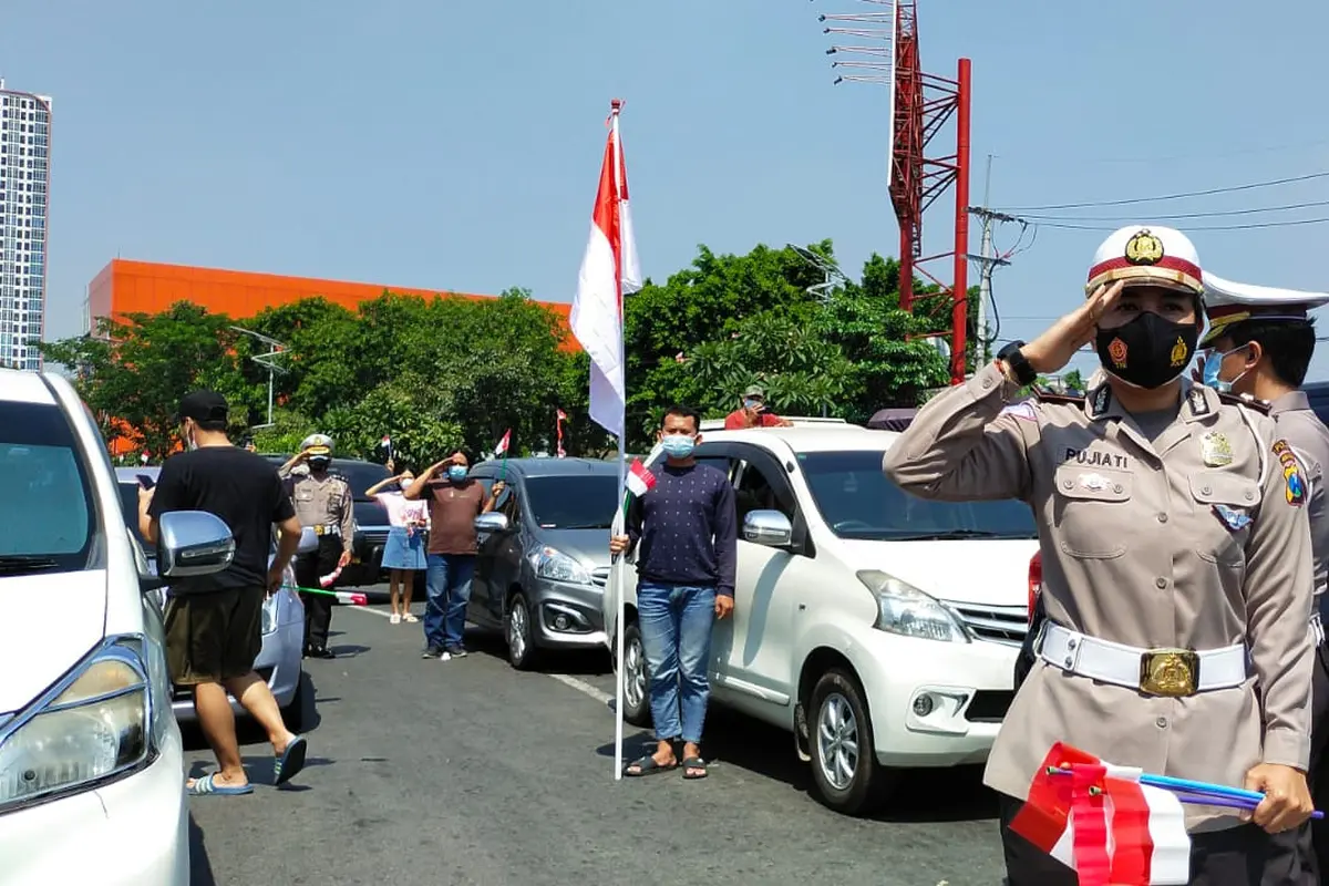 Pengendara di Surabaya menyanyikan lagu Indonesia Raya menyambut HUT RI. (Dian Kurniawan/Liputan6.com)
