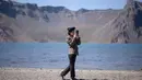 Gambar pada 11 September 2019 memperlihatkan siswa Korea Utara bermain ponsel di depan danau Chonji atau 'Heaven lake' saat mengunjungi kawasan Gunung Paektu di Samjiyon. 'Heaven lake' atau Danau surga ini ada di ketinggian 2.190 mdpl dan punya kedalaman 384 meter. (Photo by Ed JONES / AFP)