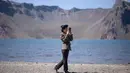 Gambar pada 11 September 2019 memperlihatkan siswa Korea Utara bermain ponsel di depan danau Chonji atau 'Heaven lake' saat mengunjungi kawasan Gunung Paektu di Samjiyon. 'Heaven lake' atau Danau surga ini ada di ketinggian 2.190 mdpl dan punya kedalaman 384 meter. (Photo by Ed JONES / AFP)