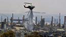 <p>Helikopter pemadam kebakaran menyemprotkan air saat terjadi kebakaran hutan dekat kilang minyak di Agioi Theodoroi. (Valerie GACHE/AFP)</p>