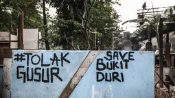 Mural hiasi dinding rumah yang terkena penertiban di kawasan bantaran Kali Ciliwung, Kelurahan Bukit Duri, Jakarta, Selasa (11/7). Sebanyak 345 bidang bangunan ditertibkan hari ini dengan target 333 kepala keluarga (KK). (Liputan6.com/Faizal Fanani)