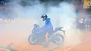 Pembalap asal Turki itu melakukan aksi freestyle dengan teknik wheelie dan donuts. Aksi donuts yang dilakukan Toprak Razgatlioglu sampai membuat SMK Negeri 39 Jakarta menjadi kepulan asap. (Bola.com/M Iqbal Ichsan)