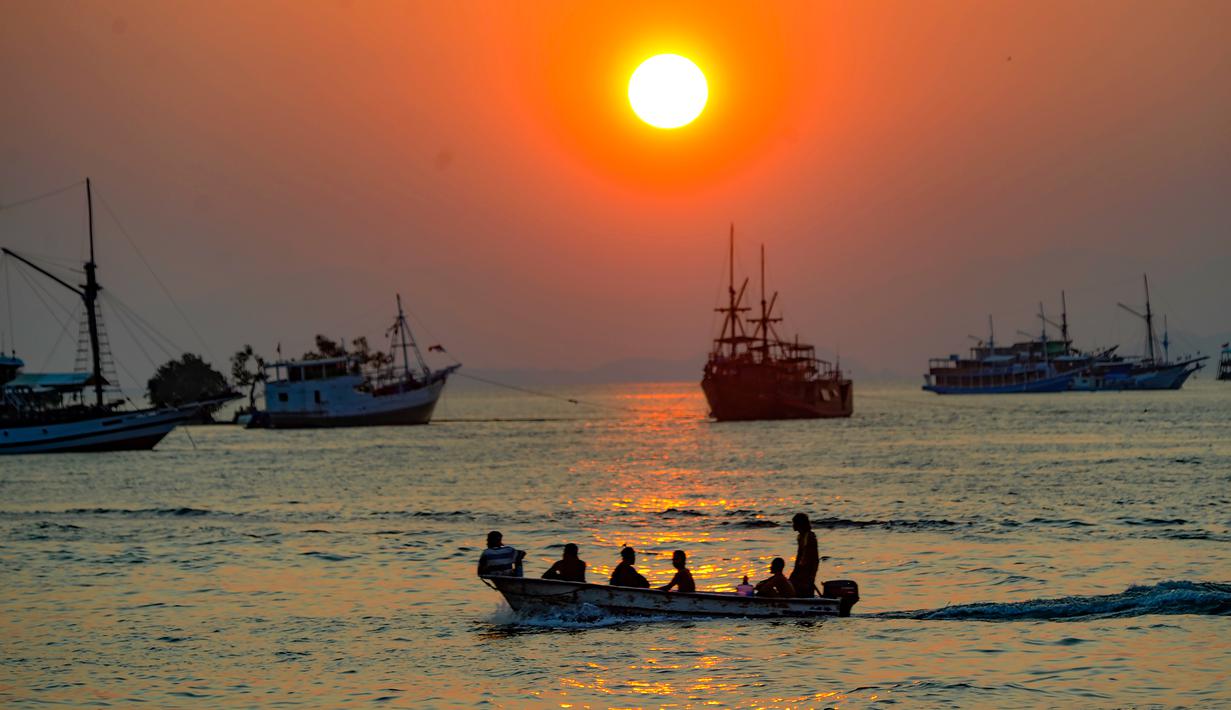 Dari tepi pantai hingga perbukitan, pengunjung dapat menikmati cahaya senja yang berpadu dengan suasana damai, diiringi bunyi lonceng gereja dan panggilan azan magrib. Tampak dalam foto, Sebuah perahu melintas di perairan Labuan Bajo, Flores, Nusa Tenggara Timur sesaat sebelum matahari terbenam. (merdeka.com/Arie Basuki)