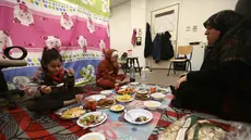 Seorang perempuan pengungsi yang tinggal bersama keluarganya di ruang kelas sekolah, setelah melarikan diri dari serangan udara Israel di pinggiran selatan Beirut, Lebanon, duduk untuk berbuka puasa bersama, pada 7 Maret 2026. Momen berbuka puasa Ramadan 1447 Hijriah di Beirut, Lebanon, berlangsung dalam situasi penuh keprihatinan. (Ibrahim AMRO/AFP)