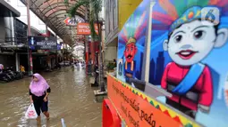 Warga melintas di kawasan pertokoan Pasar Baru, Jakarta, Kamis (2/1/2020). Pasca banjir yang melanda sejumlah titik di Jakarta pada Rabu (1/1), aktivitas perniagaan di kawasan Pasar Baru masih terlihat sepi dan sebagian toko masih tutup. (Liputan6.com/Helmi Fithriansyah)