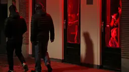 Orang-orang berjalan melewati rumah bordil di Red Light District Amsterdam, Belanda, Rabu (3/4). Pemerintah Amsterdam melarang tur prostitusi di kawasan tersebut karena banyak keluhan dari pekerja seks komersial (PSK). (REUTERS/Yves Herman)
