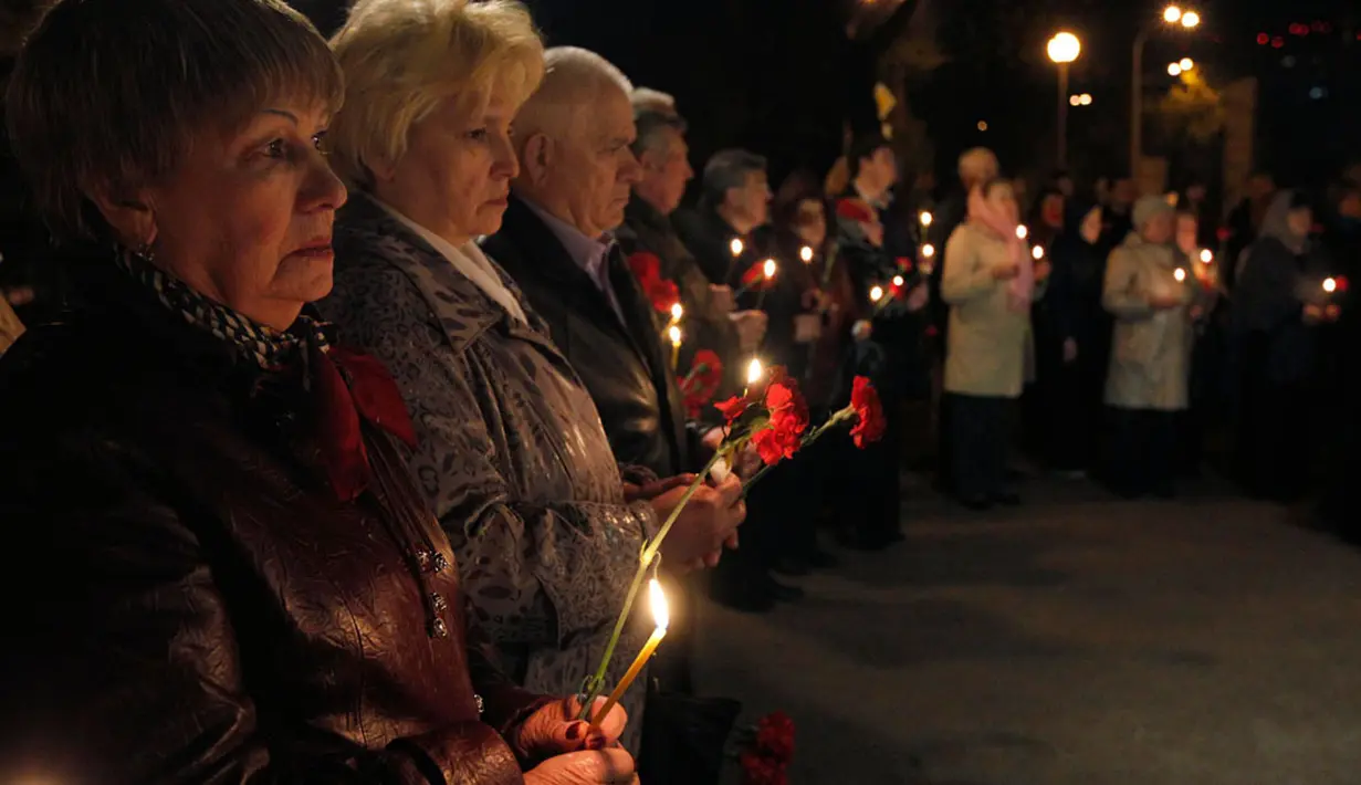Beberapa orang memegang bunga dan lilin mengenang korban bencana nuklir Chernobyl saat upacara peringatan 28 tahun bencana nuklir Chernobyl, di Kiev, Ukraina (26/4/2014). (REUTERS/Valentyn Ogirenko)