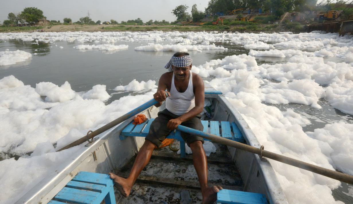 Seorang pria menaiki sampan di Sungai Yamuna yang tercemar di New Delhi, Sabtu (8/7). Sungai Yamuna sangat penting bagi masyarakat India karena banyak perayaan yang dilakukan di sungai tersebut. (DOMINIQUE FAGET / AFP)