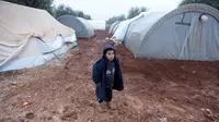 Seorang bocah laki-laki berdiri di jalanan berlumpur di kamp pengungsi Bab Al-Salam, dekat perbatasan Suriah-Turki, Provinsi Aleppo Utara, Senin (26/12). Di sini tercatat sekitar ribuan warga yang telah lama hidup di tenda. (REUTERS/Khalil Ashawi)