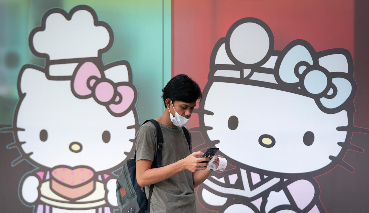 Seorang pria yang mengenakan masker berjalan melewati iklan Hello Kitty di luar sebuah toko serba ada di Kuala Lumpur, Malaysia, Senin (4/5/2020). Malaysia sejak lockdown sejatinya baru akan berakir pekan depan. (AP/Vincent Thian)