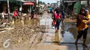 Warga melintas di sepanjang jalan yang dipenuhi lumpur di komplek Pondok Gede Permai Jatiasih, Bekasi, Jumat (22/04). Banjir yang telah merendam ratusan rumah warga mengakibatkan air lumpur mengendap. (Liputan6.com/Fery Pradolo)