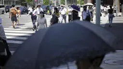 Orang-orang berjalan di atas penyeberangan pejalan kaki di bawah terik matahari di Tokyo, Selasa (28/6/2022). Pemerintah Jepang mengeluarkan peringatan untuk kemungkinan pemadaman listrik di wilayah Tokyo pada hari Senin (27/6), meminta kantor dan penduduk untuk menghemat energi karena wilayah ibu kota dilanda panas terik. (AP Photo/Eugene Hoshiko)