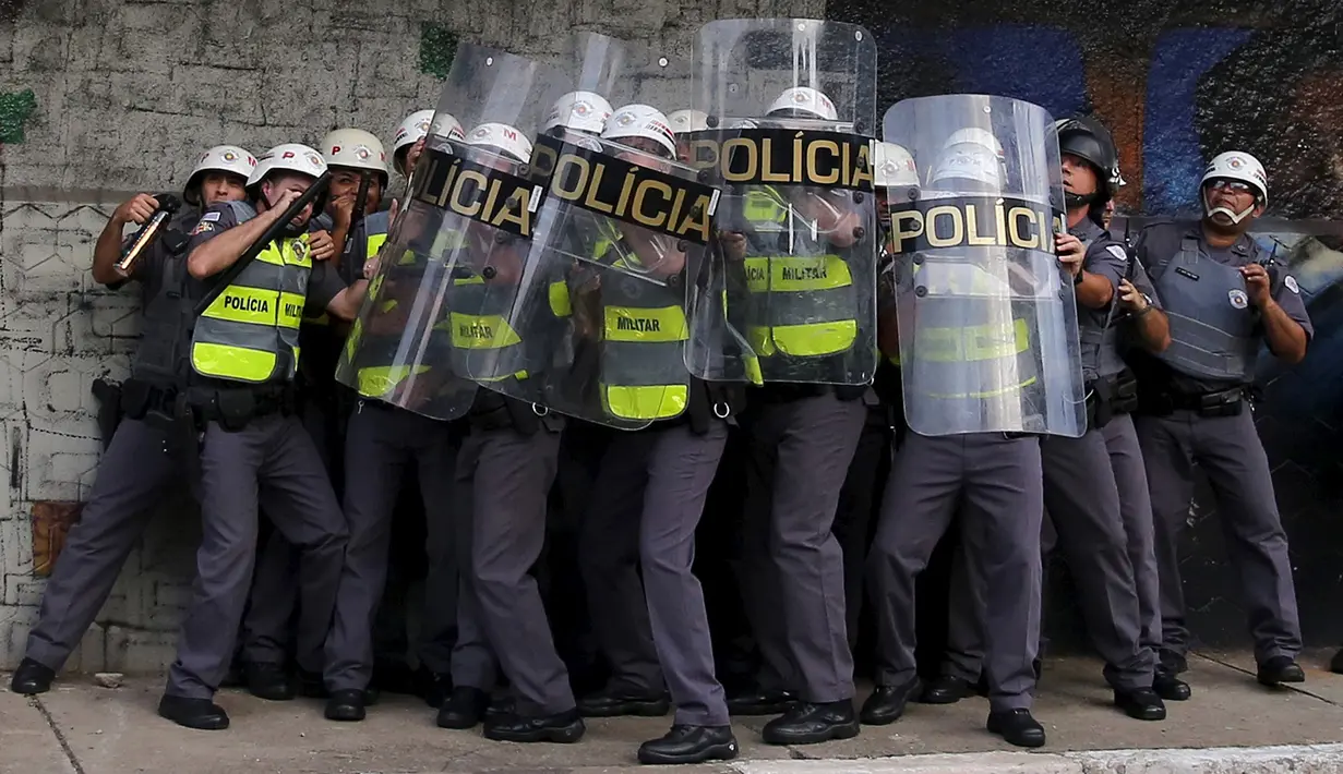 Polisi Anti Huru hara melindungi diri di balik perisai saat diserang para demonstran, Brasil, Jumat (8/1/2016). Pengunjuk rasa protes terhadap kenaikan tarif untuk bus kota di Sao Paulo. (Reuters/Nacho Doce)