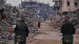 Sedikitnya 235.000 warga Palestina di Jalur Gaza terdampak krisis akibat cuaca ekstrem yang memperparah dampak perang berkepanjangan di wilayah tersebut. Tampak dalam foto, seorang wanita Palestina berjalan di sepanjang jalan yang dikelilingi bangunan-bangunan yang hancur akibat serangan udara dan darat Israel di lingkungan Sheikh Radwan, Kota Gaza, Selasa, 30 Desember 2025. (AP Photo/Abdel Kareem Hana)