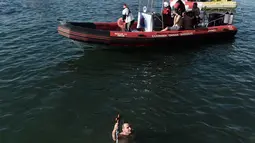 Seorang perenang memegang sebuah salib kayu yang dilemparkan ke laut saat restu upacara air menandai hari Epiphany Orthodox, di pelabuhan Thessaloniki, Yunani utara, (6/1). (AFP Photo/Sakis Mitrolidis)