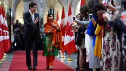 PM Kanada Justin Trudeau dan aktivis muda pemenang Penghargaan Nobel Perdamaian, Malala Yousafzai saat akan menghadiri upacara pemberian hadiah kewarganegaraan di Gedung Parlemen Kanada di Ottawa, Rabu (12/4). (Justin Tang/The Canadian Press via AP)