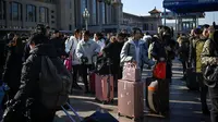 Calon pemudik menunggu kereta mereka di luar pintu masuk stasiun kereta api Beijing, Jumat (10/1/2020). Puluhan ribu warga China telah memulai migrasi manusia terbesar di dunia meninggalkan kota-kota besar menuju kampung halaman untuk merayakan Tahun Baru Imlek. (WANG ZHAO/AFP)