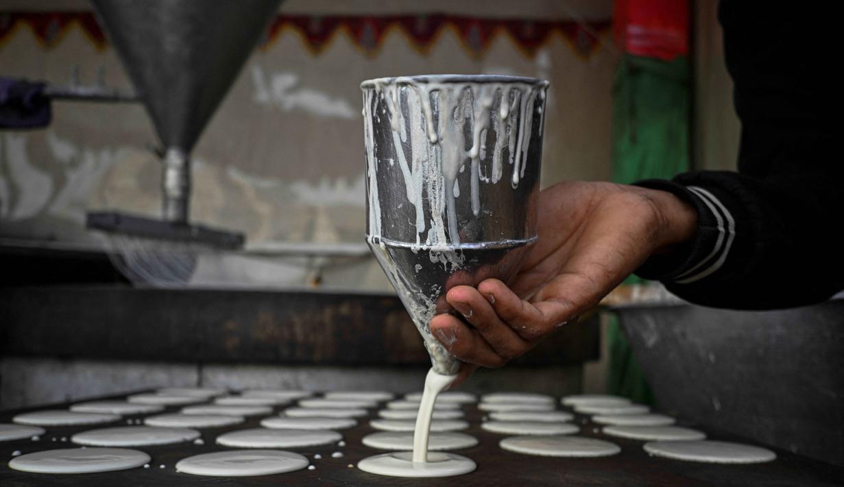 Berasal dari Timur Tengah (Mesir, Suriah, Palestina), Qatayef identik sebagai sajian berbuka puasa. Tampak dalam foto, seorang pembuat dan pedagang roti Mesir membuat Qatayef, pancake tradisional yang dibuat selama bulan puasa suci Ramadan, di tokonya, Kairo, Mesir, pada Kamis 12 Maret 2026. (Khaled DESOUKI/AFP)