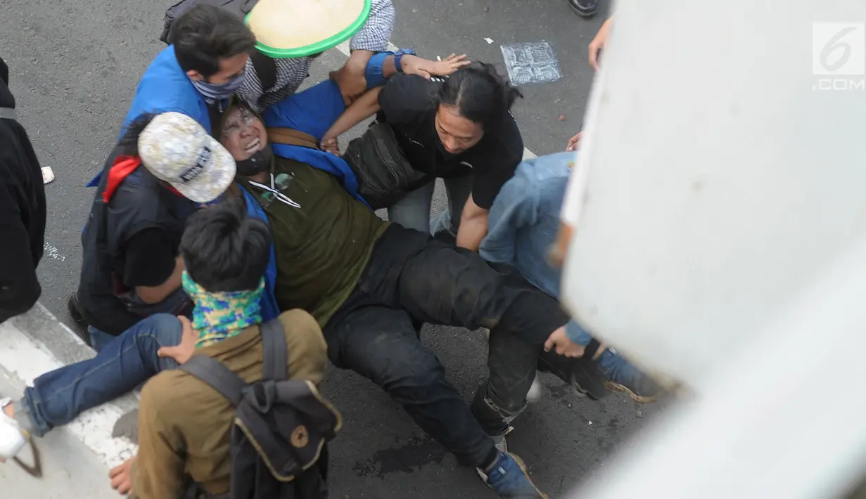 Sejumlah mahasiswa menggotong rekan mereka yang terluka saat demonstrasi menolak pengesahan RUU KUHP dan revisi UU KPK di depan Gedung DPR, Jakarta, Selasa (24/9/2019). Sejumlah mahasiswa tumbang setelah polisi menembakkan gas air mata untuk membubarkan demonstrasi. (merdeka.com/Arie Basuki)