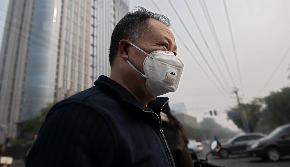 Seorang pria beraktivitas mengenakan masker pelindung untuk menghindari polusi udara buruk di Beijing (22/10). (AFP Photo/Nicolas Asfaouri)