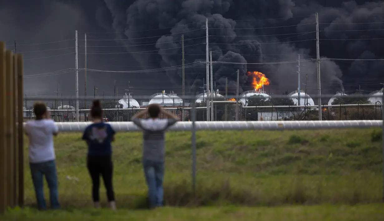 Warga mengamati kebakaran pabrik TPC Group yang meledak di Port Neches, Texas (27/11/2019). Dua ledakan besar 13 jam terpisah membakar pabrik kimia dan menyebabkan tiga pekerja terluka. (Marie D. De Jesús/Houston Chronicle via AP)