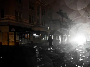 Seorang pria berjalan melewati jalanan yang tergenang air setelah Badai Milton mendarat di Fort Myers, Florida, pada tanggal 9 Oktober 2024. (CHANDAN KHANNA/AFP)