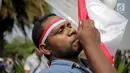 Massa Aliansi Masyarakat Indonesia Timur mencium bendera Merah Putih saat berunjuk rasa di depan Istana Merdeka, Jakarta, Senin (2/9/2019). Massa menyatakan bahwa Papua tetap NKRI dan meminta pemerintah mengusut tuntas kasus rasis yang berujung konflik. (Liputan6.com/Faizal Fanani)