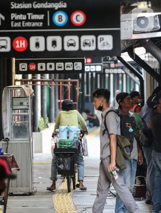 Warga melintas saat pekerja menyelesaikan pembuatan ruko untuk UMKM di stasiun Gondangdia, Jakarta, Sabtu (16/10/2021). Pembuatan ruko untuk para pedaganag di kawasan sekitar stasiun tersebut bertujuan agar terlihat lebih rapi dan modern. (Liputan6.com/Johan Tallo)