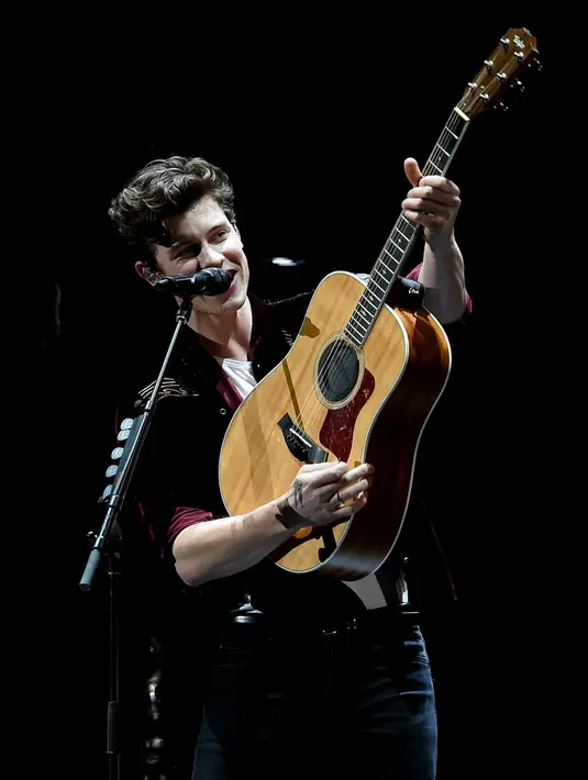 Shawn Mendes memang selalu identik dengan gitar akustik miliknya. (Liputan6.com/AFP)