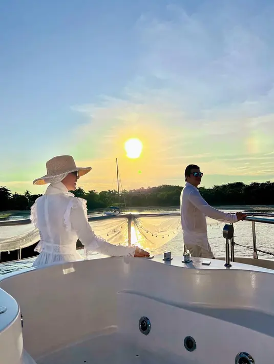 3. Menikmati golden hour di atas kapal, Syahrini dan Reino Barack tampil serasi dengan busana serba putih.