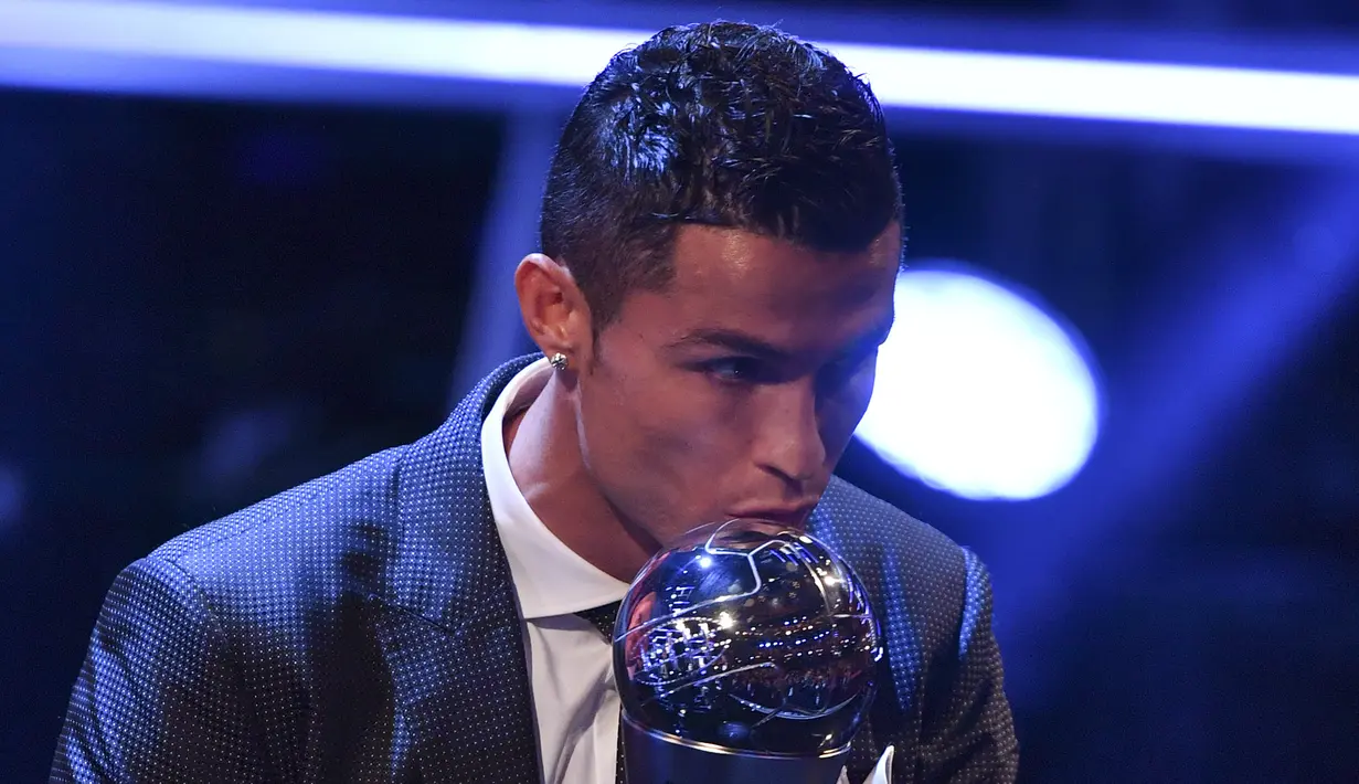 Bintang Real Madrid, Cristiano Ronaldo, mencium trofi pemain terbaik FIFA 2017 di London, Senin (23/10/2017) Ronaldo berhasil mengalahkan Lionel Messi dan Neymar yang juga menjadi nominasi. (AFP/Ben Stansall)