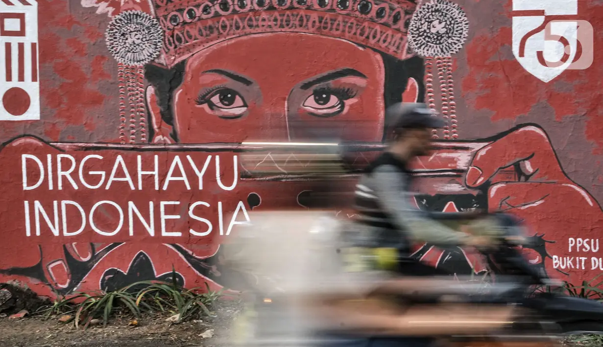 Pengendara motor melintasi mural bertema HUT ke-75 RI di Jalan Abdullah Syafei, Jakarta, Minggu (16/8/2020). Jelang HUT ke-75 RI, mural bernuansa Merah Putih banyak menghiasi jalanan Ibu Kota guna memberi semangat nasionalisme kepada warga di tengah pandemi COVID-19. (merdeka.com/Iqbal S.Nugroho)