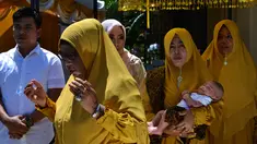 Tokoh adat dan agama menggendong bayi pada ritual 'peutron tanoh aneuk' (turun tanah anak) di Banda Aceh, Aceh, Senin (15/7/2019). Ritual turun tanah anak yang telah menjadi tradisi sakral bagi masyarakat Aceh yang dilaksanakan pada saat bayi berusia 44 hari. (CHAIDEER MAHYUDDIN / AFP)
