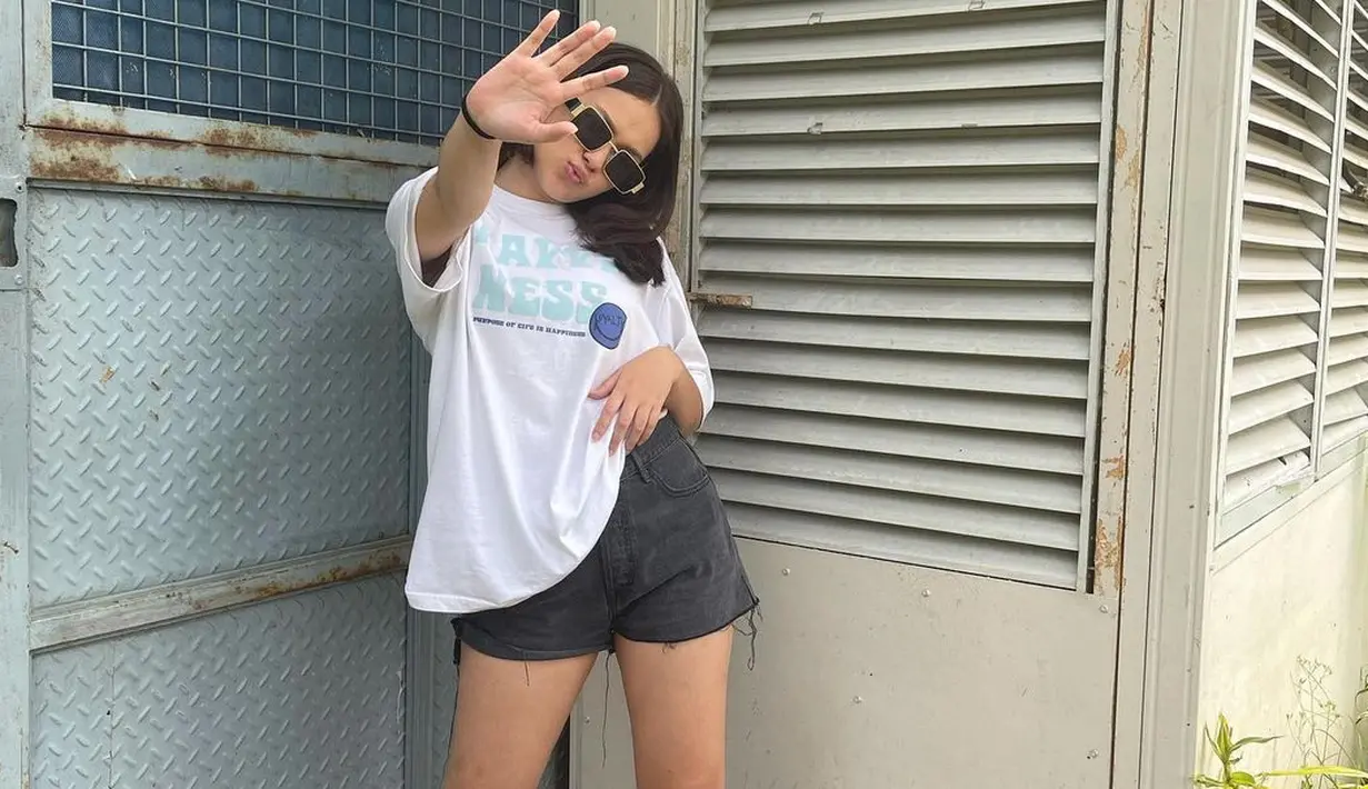 Inspirasi tampil kasual ala Rebecca Klopper, yaitu mengenakan oversized white t-shirt favoritmu, dipadu dengan short pants, kaus kaki panjang selutut, dan sunglasses. Kamu siap pergi. Foto: Instagram.