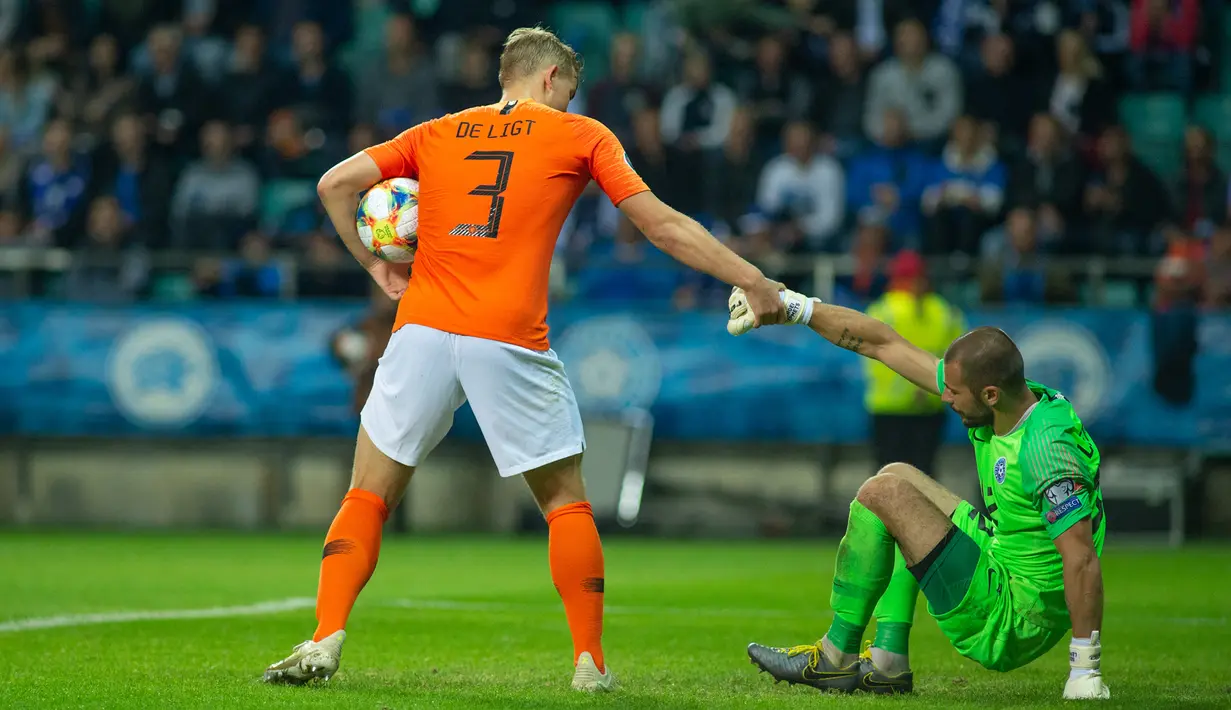 Bek Belanda, Matthijs De Ligt (kiri) membantu penjaga gawang Estonia, Sergei Lepmetz saat keduanya bertanding dalam kualifikasi Grup C Euro 2020, di Tallinn, Estonia, Senin (9/9/2019). Belanda mengalahkan Estonia dengan skor 4-0. (Raigo Pajula/AFP)