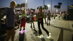 Orang-orang bermain sepatu roda di sepanjang trotoar Venice Beach di Venice, California, Kamis (3/9/2020). Menurut data Google, pencarian terkait sepatu roda dari Maret hingga Mei di Amerika Serikat meningkat hampir empat kali lipat. (Mario Tama/Getty Images/AFP)