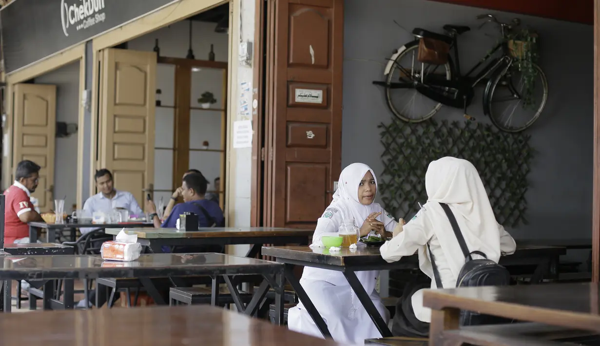 Pengunjung duduk di sebuah restoran di Bireuen, Aceh, Rabu (5/9). Pemerintah Kabupaten Bireuen mengharamkan perempuan dan lelaki yang nonmuhrim minum kopi semeja di restoran, kafe, bahkan di warung kopi biasa. (AFP PHOTO/AMANDA JUFRIAN)