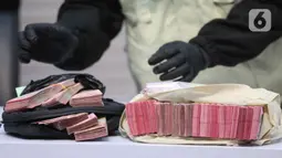 Barang bukti tersebut di antaranya beberapa dokumen, Barang Bukti Elektronik (BBE), beberapa pasang sepatu, serta uang tunai sebesar Rp 335,4 juta. Tampak dalam foto, tumpukan uang barang bukti terkait Operasi Tangkap Tangan (OTT) Bupati Tulungagung, Gatut Sunu Wibowo, diperlihatkan petugas di Gedung Merah Putih Komisi Pemberantasan Korupsi (KPK), Jakarta, Sabtu (11/4/2026). (Liputan6.com/Helmi Fithriansyah)