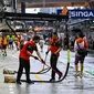 Anggota tim Ferrari menyapu pit lane setelah hujan sebelum&nbsp;balapan Formula 1 (F1) GP Singapura di Sirkuit Jalan Raya Marina Bay, Minggu, 2 Oktober 2022. (MOHD RASFAN / AFP)