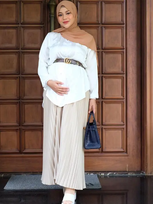 <p>Tak melulu dengan dress, menggunakan rok juga bisa tetap membuatmu stylish. Paduan kemeja dan belt melengkapi penampilan yang simple dan mudah ditiru. [Instagram/aurelie.hermansyah]</p>
