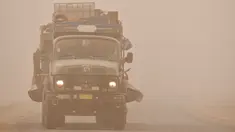 Sebuah truk melaju melalui badai pasir Musim Semi di kota Nasiriyah, di provinsi Dhi Qar, Irak selatan (5/5/2022). Irak kembali diselimuti lapisan jingga tebal karena mengalami serangkaian badai debu terbaru yang semakin sering terjadi. (AFP/Asaad Niazi)