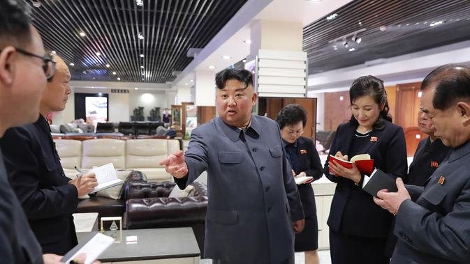Pemimpin Korea Utara, Kim Jong-un berbincang dengan stafnya ketika berada di toko furniture saat mengunjungi Taesong Department Store setelah dibuka untuk umum di Korea Utara (8/4). (KCNA VIA AFP Photo)